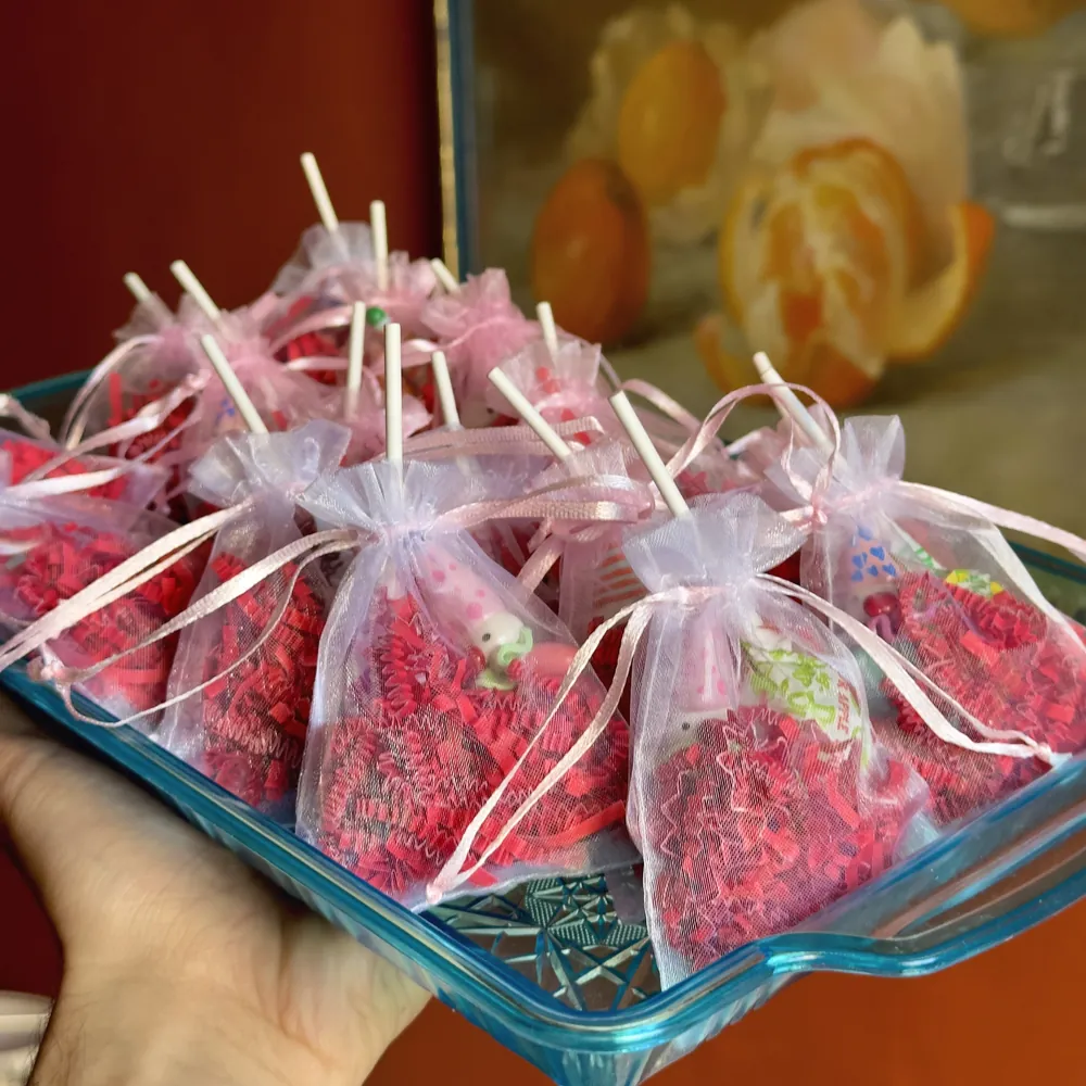 A tray of party favors wrapped in pink organza bags